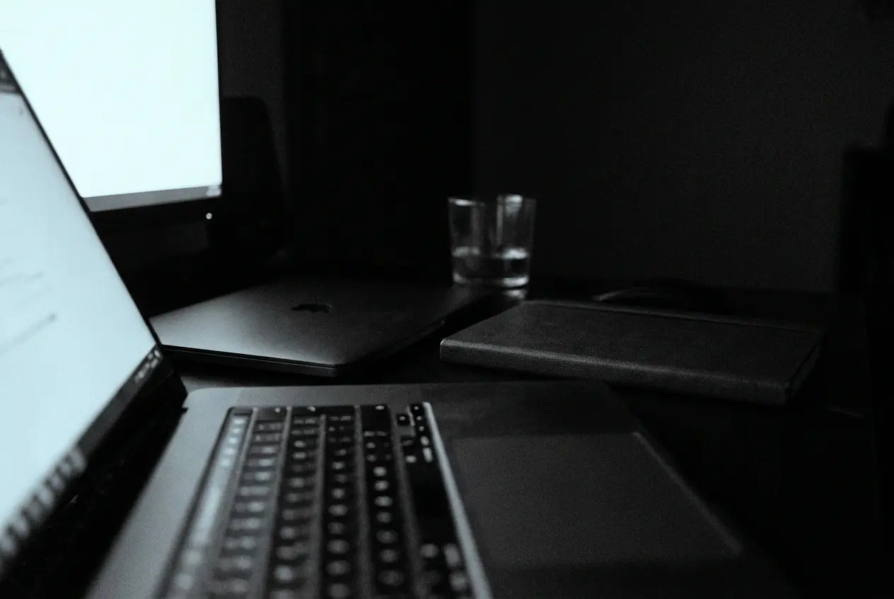 Two laptops open on a desk at night